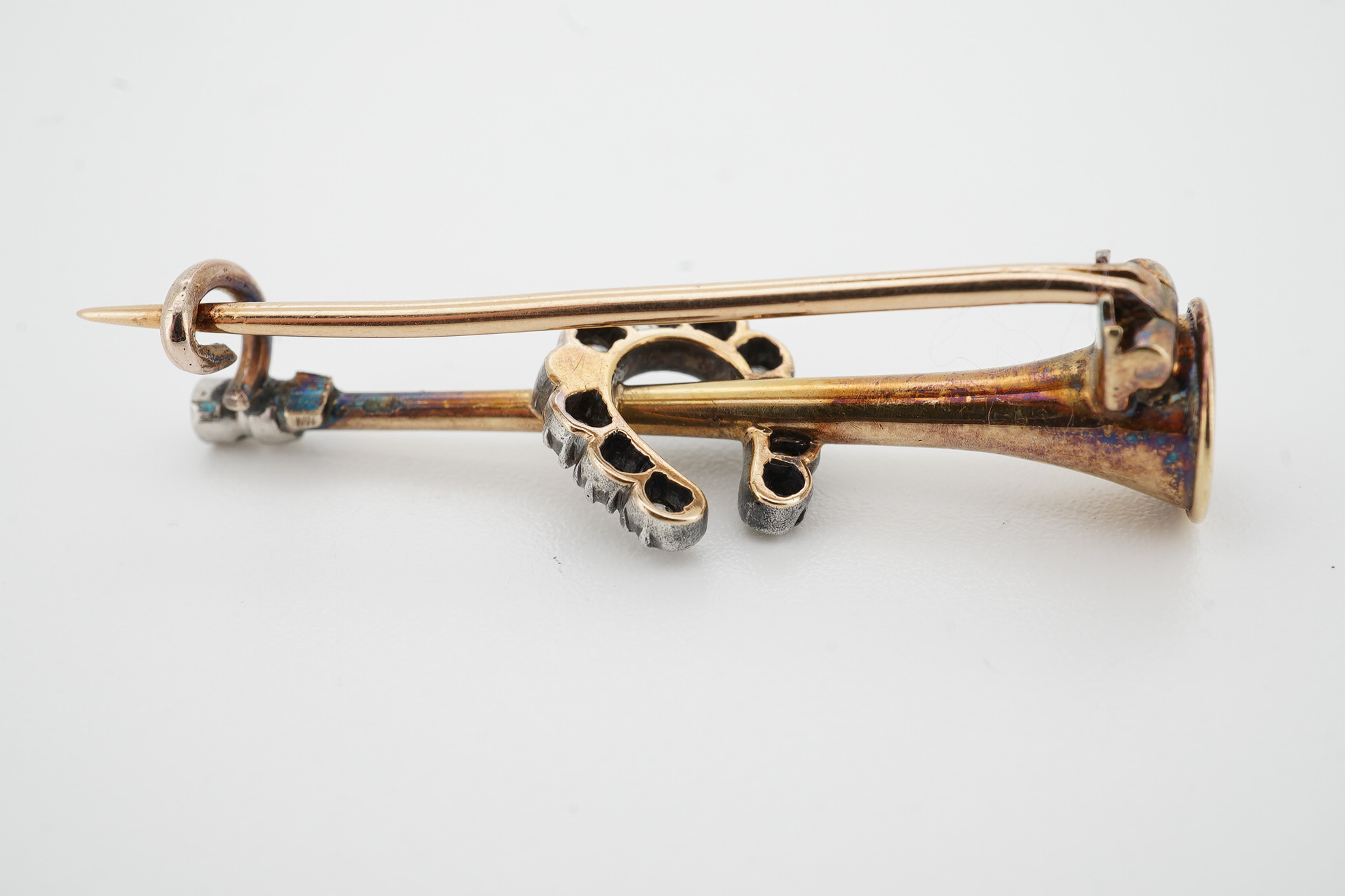 An early 20th century yellow metal and diamond cluster set horseshoe and hunting horn brooch, 36mm, gross weight 4.2 grams. Condition - fair